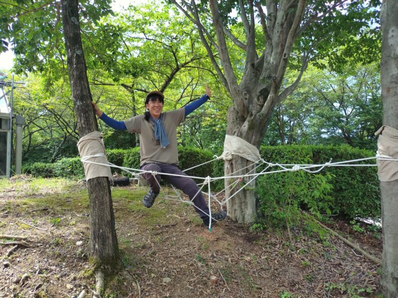 ロープを結んで作ったハンモックに乗ってみている大人