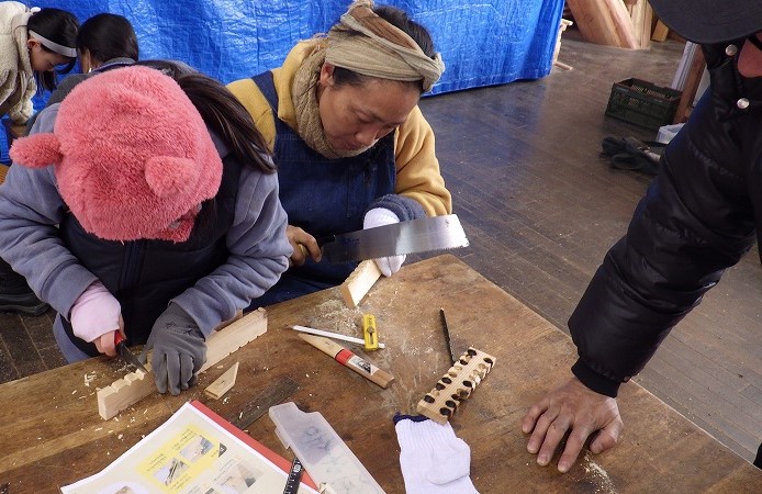削った木粉の溜まる溝を作る参加者