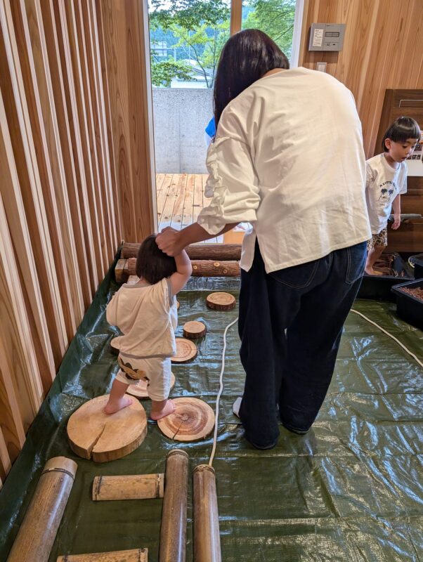 ヒノキ円盤の上を歩く2歳未満のお子さん