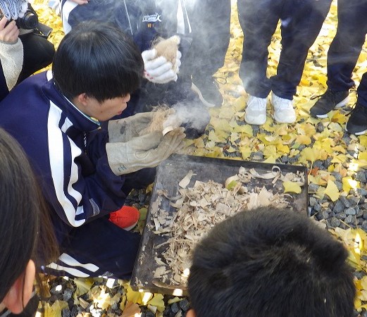 火種に空気を吹き込んで小さな火に育てる生徒さん