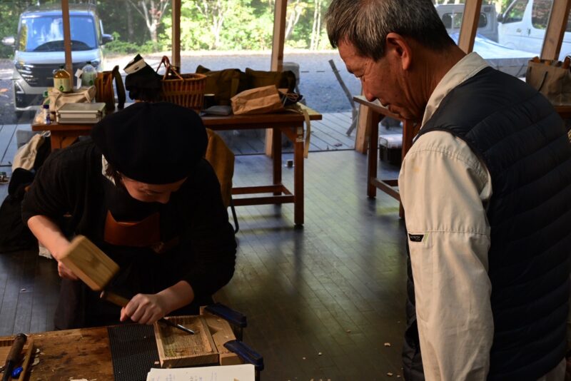 和谷盆を彫る参加者と見守る指導者