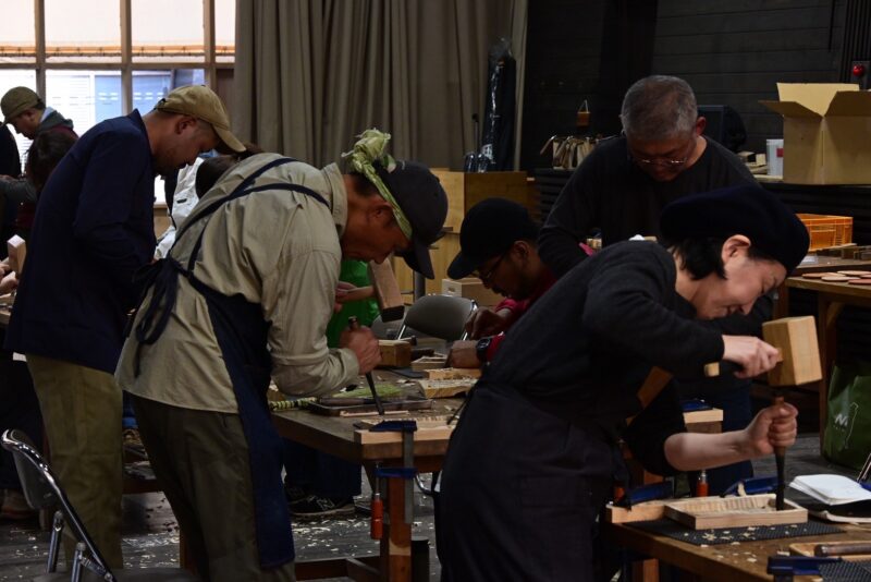 ノミや鉋といった日本の木工道具を使いながら作業する