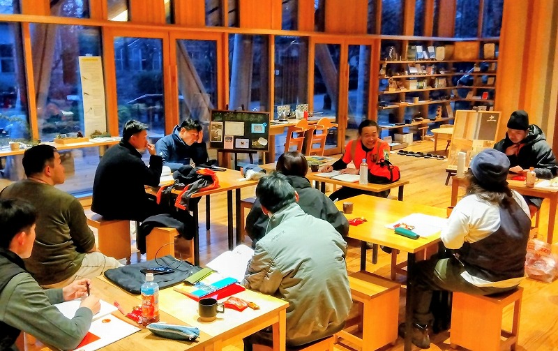 夜はテキストを見ながら室内で学ぶ参加者