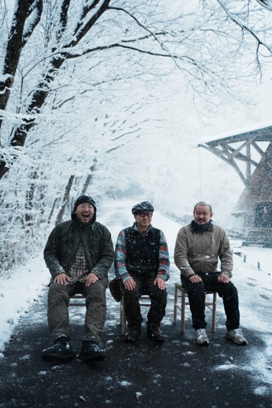 雪の中、完成した椅子員座って記念撮影をする参加者