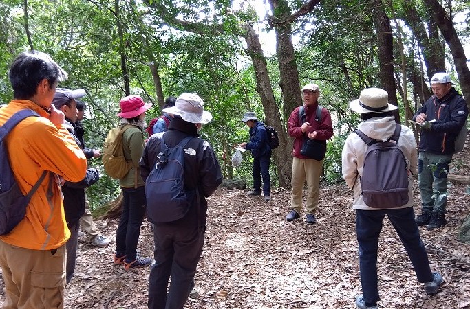 マンリョウが生えていた場所で葉粒菌について説明する小原さん