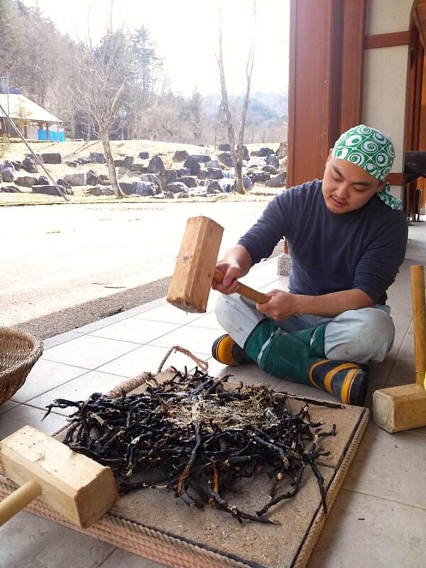 ワラビ根を叩いてデンプンを採取する前原さん